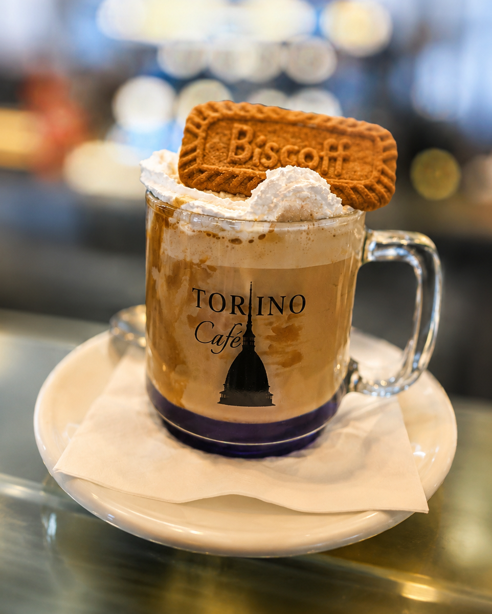 Mug of Torino Cafe coffee with whipped cream and a Biscoff cookie 